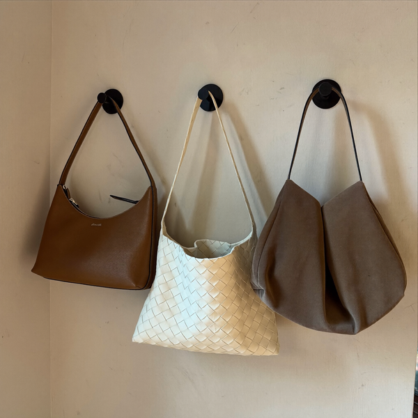 Drei Taschen an Wandhaken: Schultertasche, Flecht-Shopper und Veloursoptik-Tasche